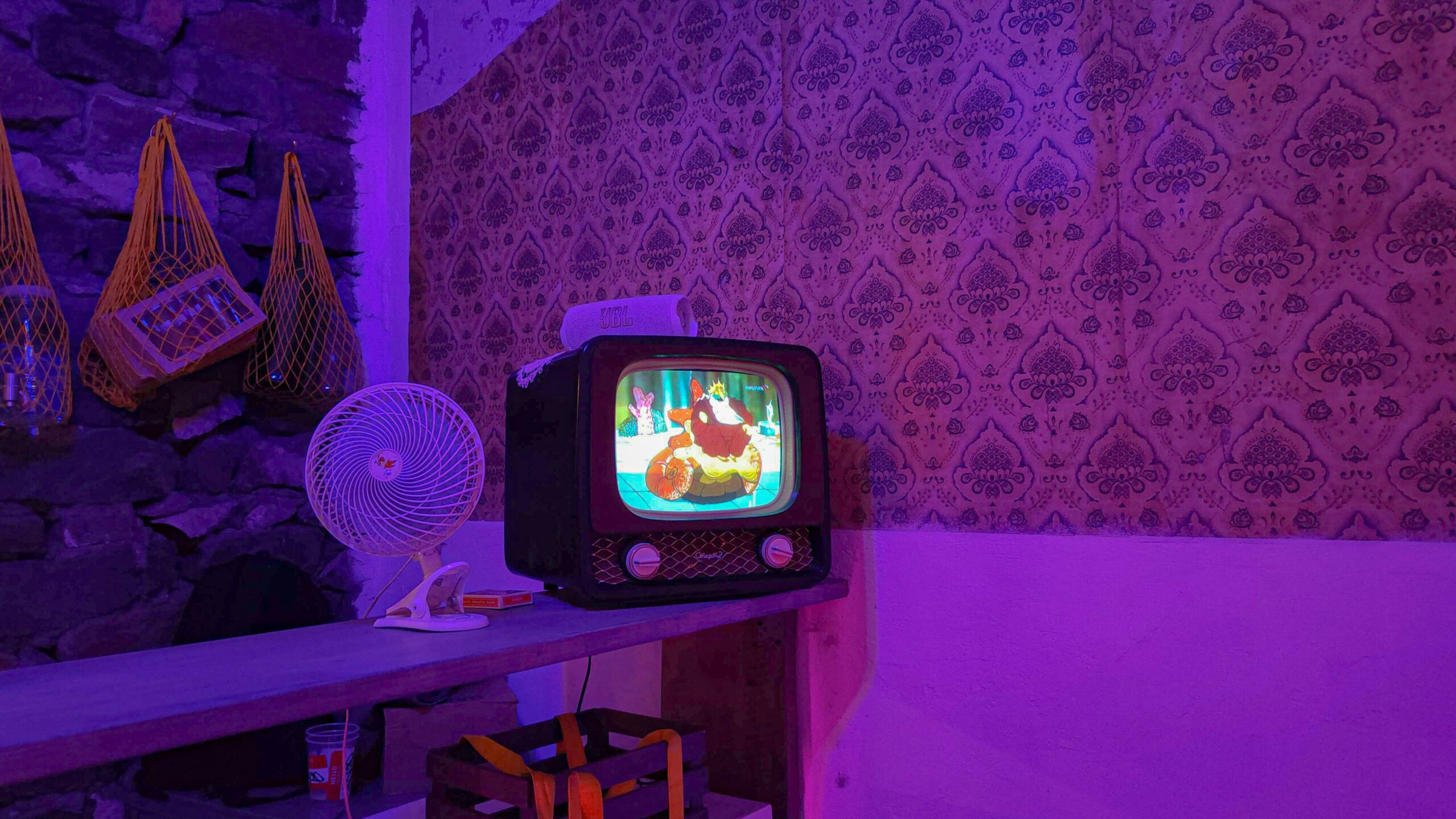 A small TV sitting on top of a wooden table. There is a cartoon on the screen.